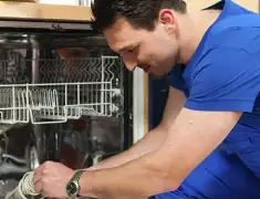 Dishwasher repair technician inspecting and servicing an open dishwasher in Gilbert, AZ