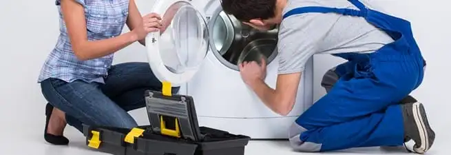 Washer repair technician inspecting a front-load washing machine with tools in Gilbert, AZ