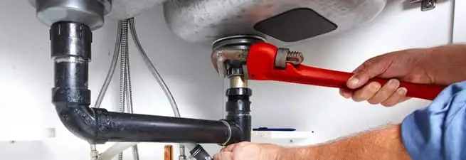 Garbage disposal repair technician tightening the sink drain and disposal connection in Gilbert, AZ