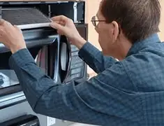 Appliance repair technician replacing a microwave vent filter in Gilbert, AZ