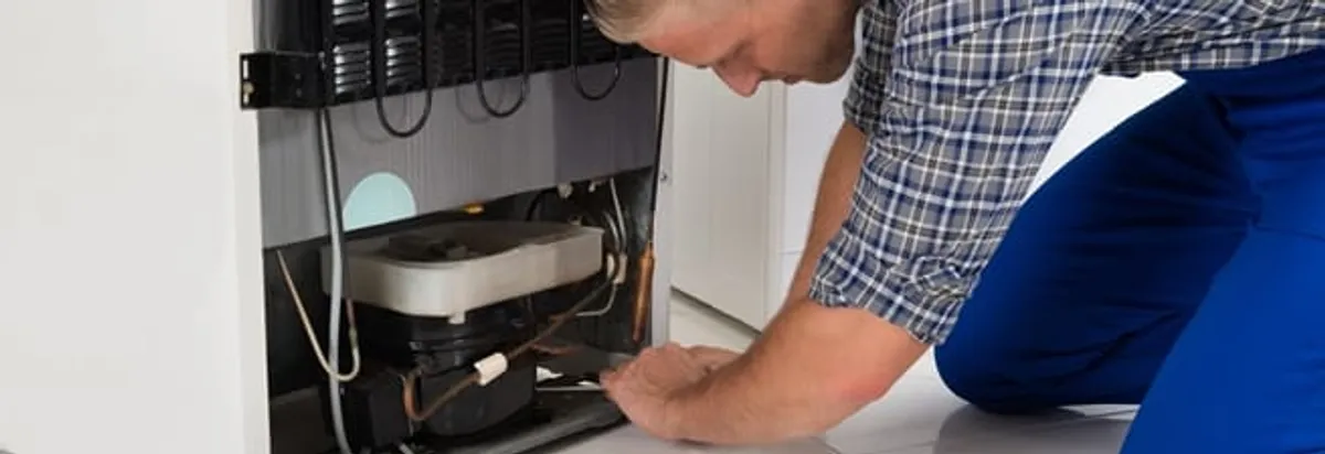 Refrigerator repair technician servicing the compressor and condenser area in Gilbert, AZ