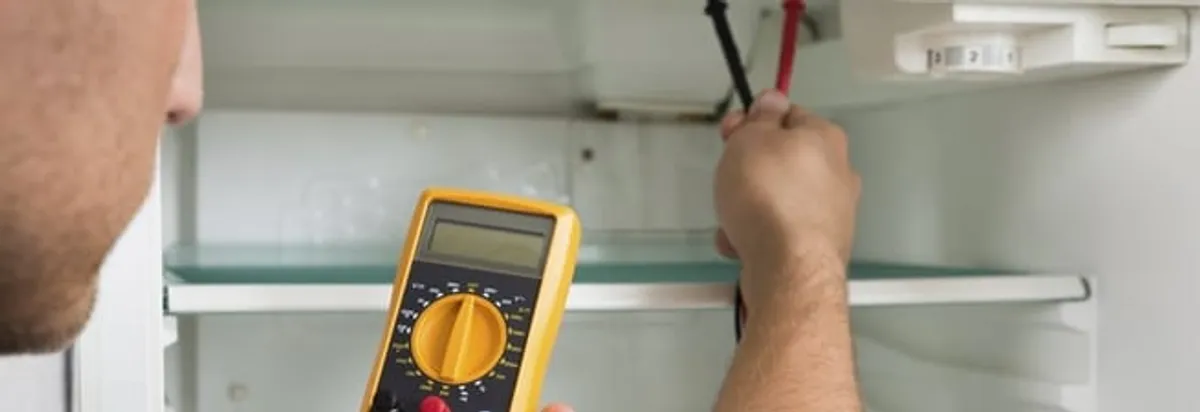 Refrigerator repair technician testing electrical components with a multimeter in Gilbert, AZ
