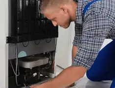 Refrigerator repair technician servicing the compressor and condenser area in Gilbert, AZ