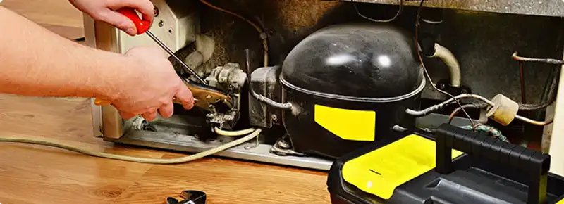 Refrigerator repair technician fixing the compressor and wiring in Gilbert, AZ