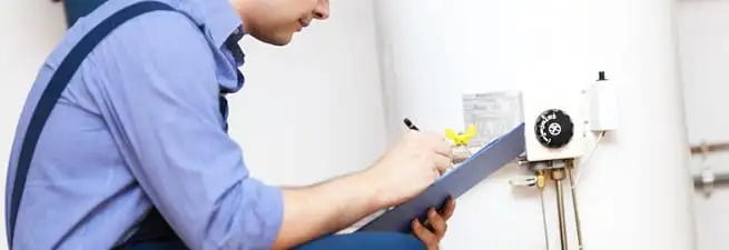 Water heater repair technician inspecting the unit and recording service notes in Gilbert, AZ