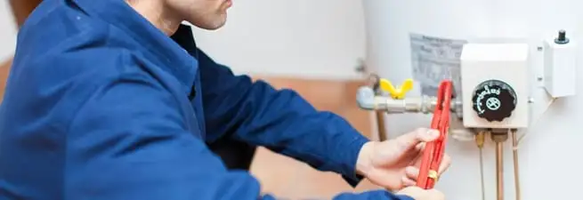 Water heater repair technician adjusting the temperature control and gas valve in Gilbert, AZ